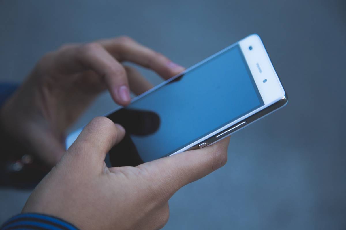 man holding mobile phone booking toss out junk removal