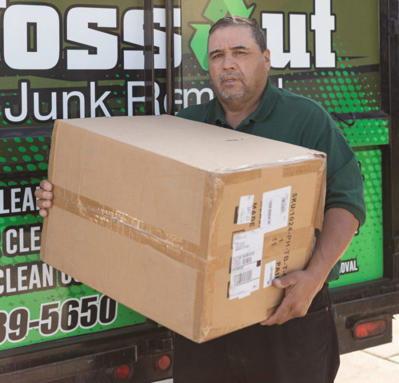 toss out junk removal pro holding a box full of eco friendly junk