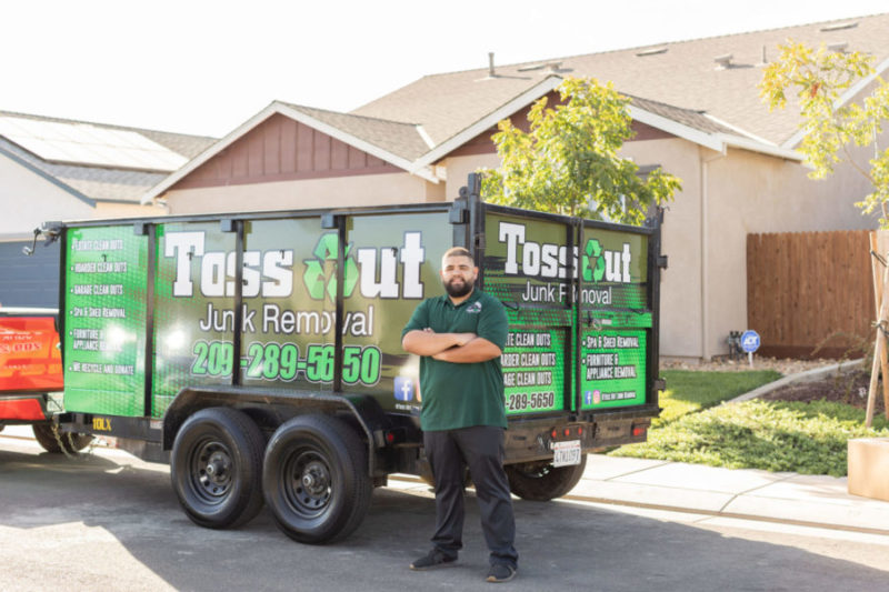 toss out junk removal pro in front of dumpster