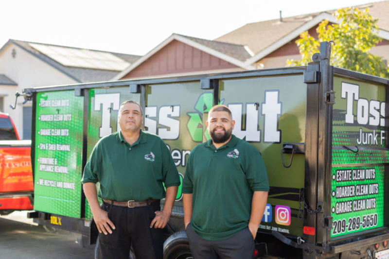 junk pros standing in front of junk removal trailer