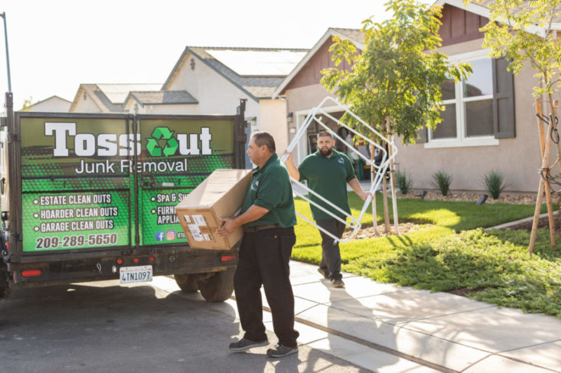 junk removal pros carrying boxes to junk removal truck